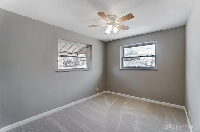 carpeted empty room featuring ceiling fan and baseboards