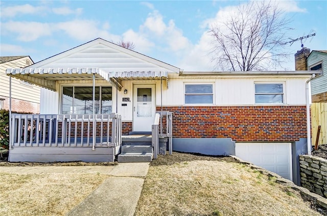 view of front of property with a garage, covered porch, and brick siding