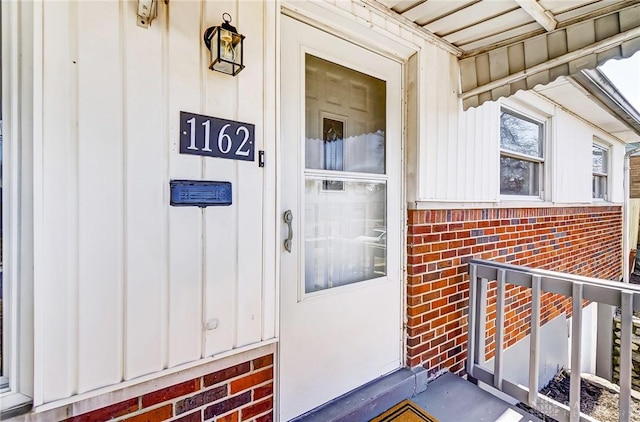 property entrance featuring board and batten siding and brick siding