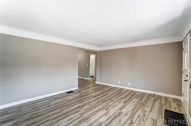 unfurnished room featuring light wood-type flooring, visible vents, and baseboards