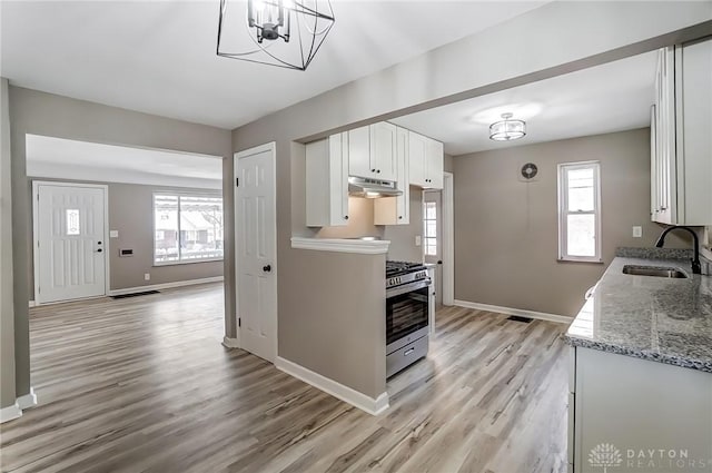 kitchen featuring plenty of natural light, stainless steel range with gas stovetop, white cabinets, and a sink