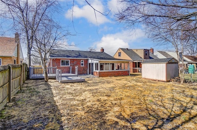 back of house featuring an outbuilding, brick siding, a storage unit, a fenced backyard, and a wooden deck