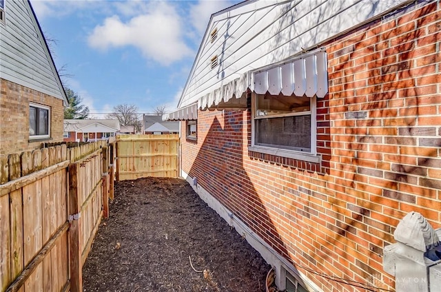 view of home's exterior with brick siding and fence