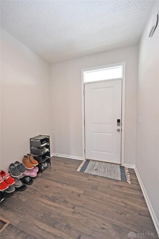 foyer featuring a textured ceiling, wood finished floors, visible vents, and baseboards