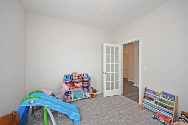 rec room featuring carpet floors, french doors, and a textured ceiling