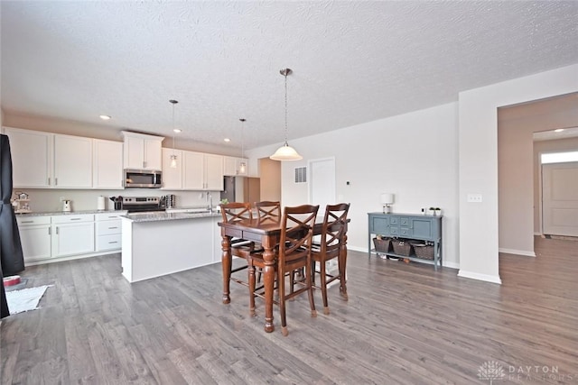 dining room with a textured ceiling, baseboards, wood finished floors, and recessed lighting