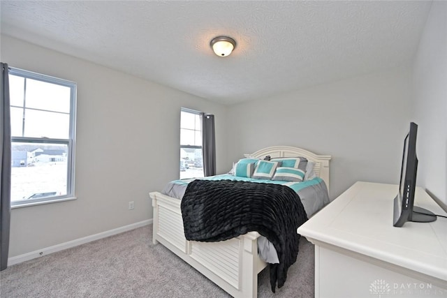 bedroom featuring carpet, multiple windows, baseboards, and a textured ceiling