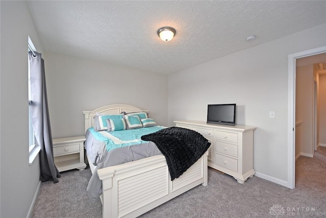 bedroom featuring light carpet, a textured ceiling, and baseboards