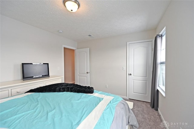 carpeted bedroom with visible vents, a textured ceiling, and baseboards