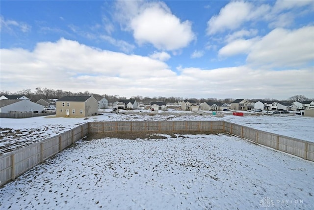 yard covered in snow with a residential view and fence