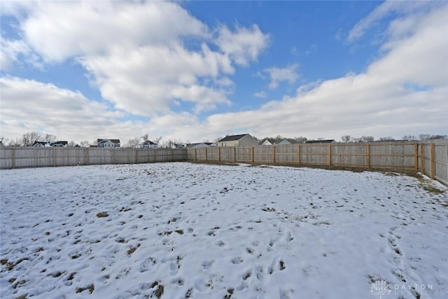 snowy yard featuring a fenced backyard