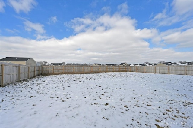 snowy yard featuring a fenced backyard