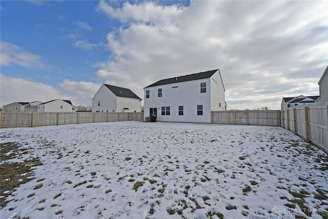 snow covered back of property with a fenced backyard