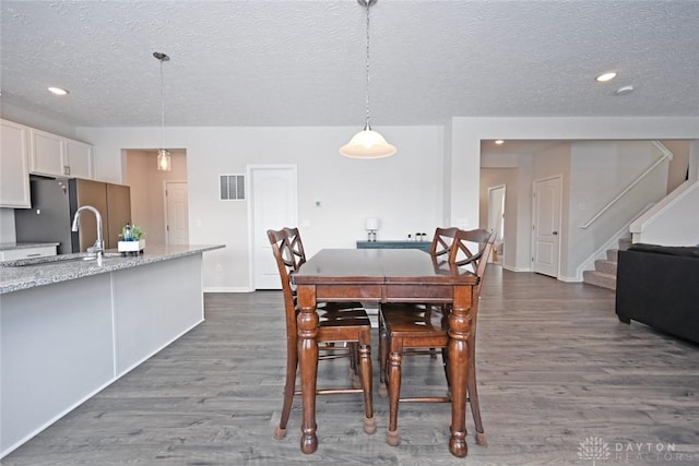 dining space with baseboards, visible vents, dark wood-type flooring, stairs, and a textured ceiling