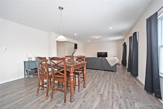 dining room with a textured ceiling, stairway, wood finished floors, and baseboards