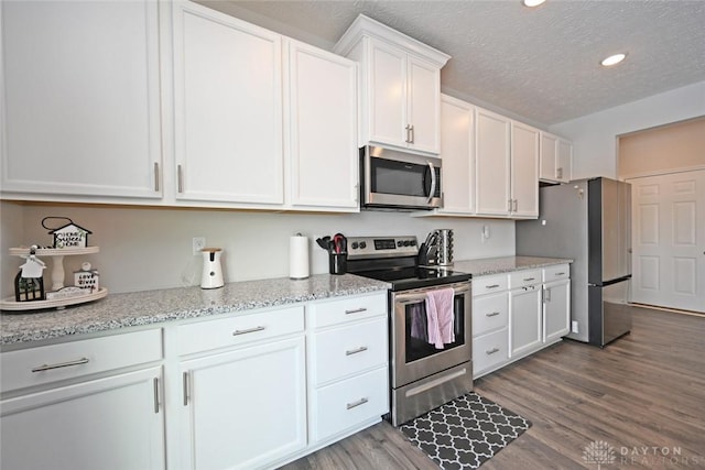 kitchen featuring light stone counters, dark wood finished floors, appliances with stainless steel finishes, white cabinets, and a textured ceiling