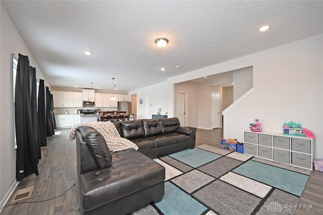 living room with recessed lighting, visible vents, a textured ceiling, wood finished floors, and baseboards