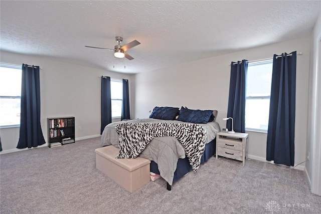 carpeted bedroom featuring ceiling fan, multiple windows, and a textured ceiling