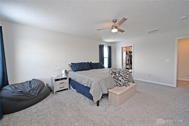 bedroom featuring baseboards, visible vents, a ceiling fan, carpet, and a walk in closet