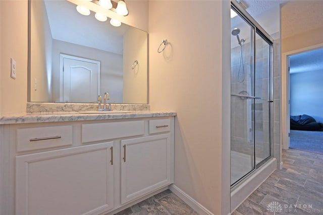 full bathroom featuring a stall shower, baseboards, and vanity