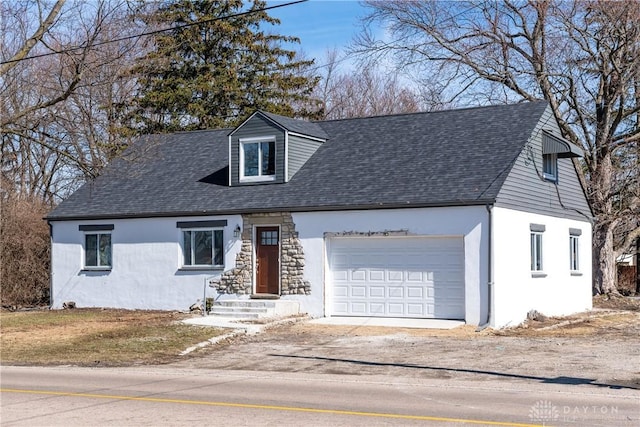 cape cod house with driveway, a shingled roof, an attached garage, and stucco siding