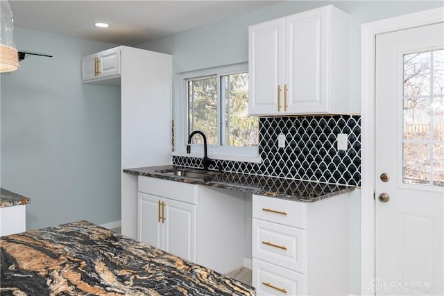 kitchen with tasteful backsplash, a healthy amount of sunlight, white cabinetry, and dark stone countertops