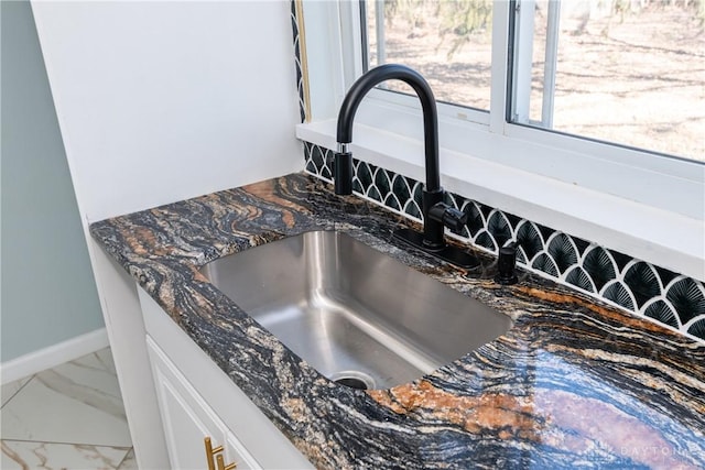 interior details featuring dark stone counters, a sink, and baseboards