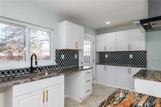 kitchen featuring marble finish floor, backsplash, dark stone counters, and a sink