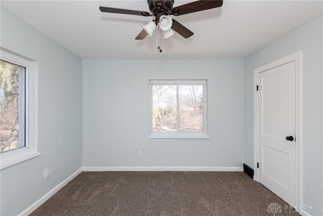 carpeted spare room with a ceiling fan and baseboards