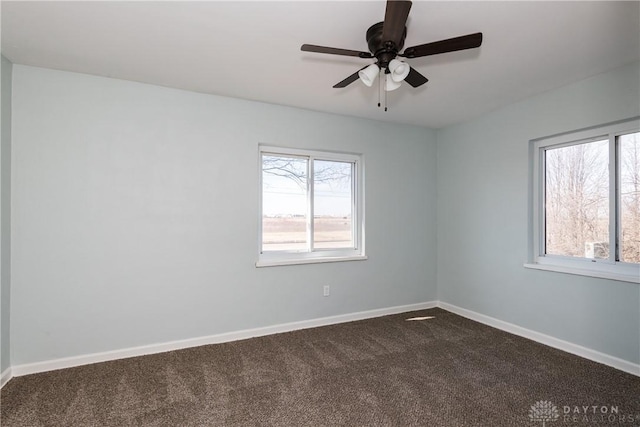 unfurnished room with a healthy amount of sunlight, dark carpet, baseboards, and ceiling fan