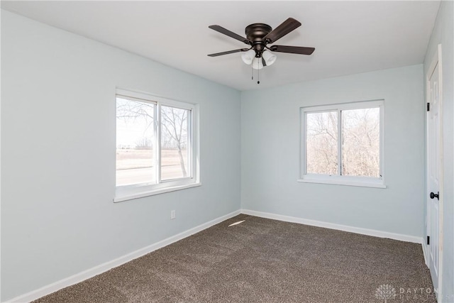 unfurnished room featuring a ceiling fan, dark carpet, and baseboards