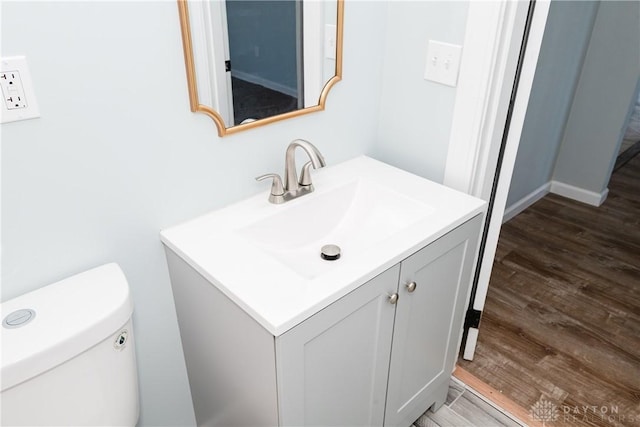 bathroom with toilet, wood finished floors, and vanity