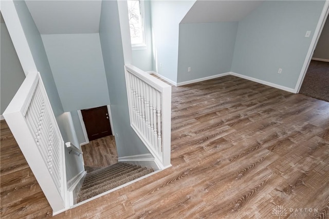 staircase with baseboards, vaulted ceiling, and wood finished floors