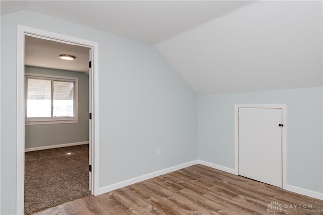 additional living space featuring vaulted ceiling, baseboards, and wood finished floors