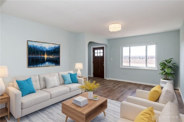 living room featuring arched walkways, baseboards, and wood finished floors