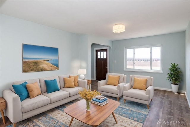 living room featuring arched walkways, wood finished floors, a wealth of natural light, and baseboards