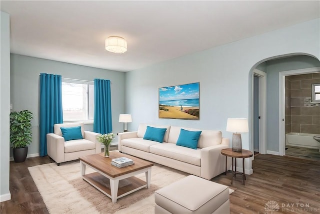 living room with baseboards, arched walkways, and wood finished floors