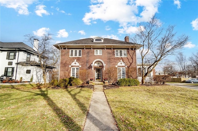 colonial home featuring a chimney, a front lawn, and brick siding