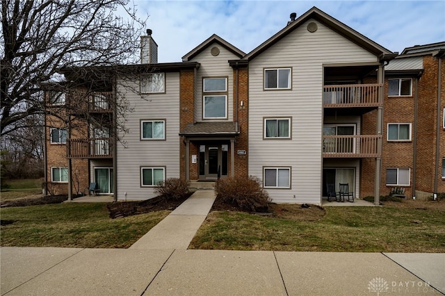 townhome / multi-family property with a front lawn and a chimney