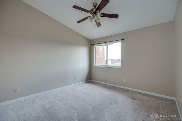 carpeted empty room with ceiling fan, baseboards, and vaulted ceiling