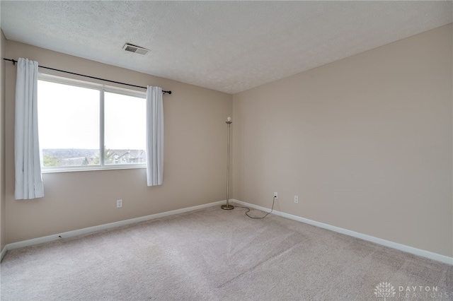 carpeted spare room featuring visible vents, a textured ceiling, and baseboards