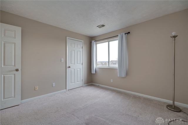 unfurnished bedroom with baseboards, visible vents, a textured ceiling, and carpet flooring