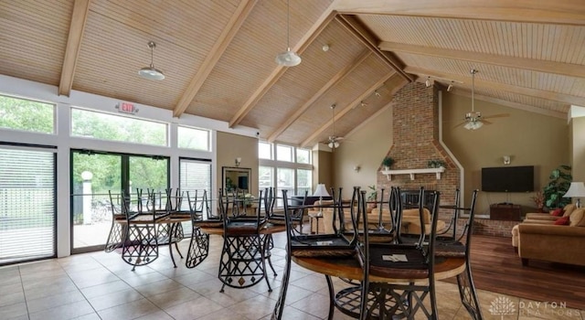 tiled dining room featuring a ceiling fan, a fireplace, high vaulted ceiling, and beam ceiling