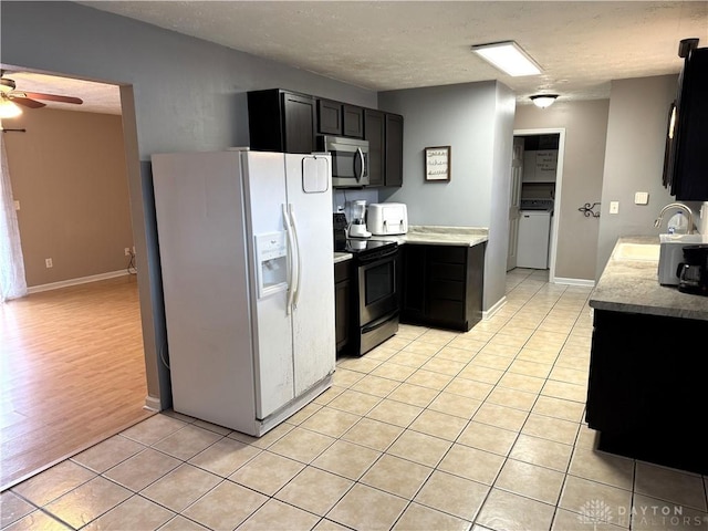 kitchen with light tile patterned floors, dark cabinets, appliances with stainless steel finishes, and a sink