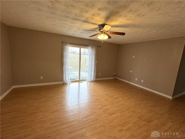 spare room with ceiling fan, a textured ceiling, wood finished floors, and baseboards