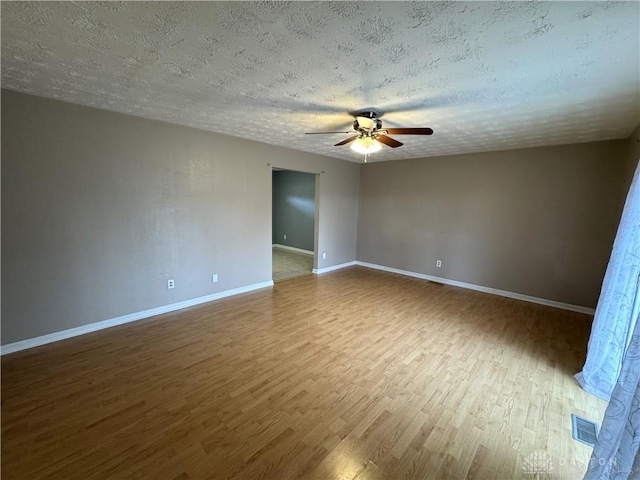 unfurnished room with baseboards, ceiling fan, visible vents, and wood finished floors