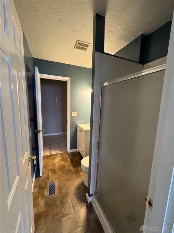 full bathroom with a shower stall, visible vents, a textured ceiling, and vanity