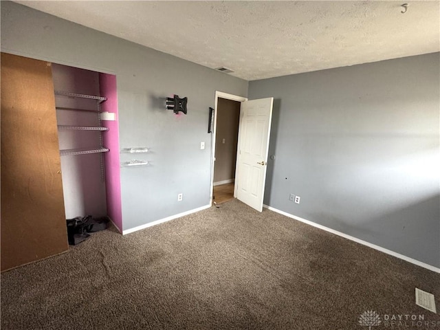 unfurnished bedroom featuring a textured ceiling, carpet floors, a closet, and baseboards