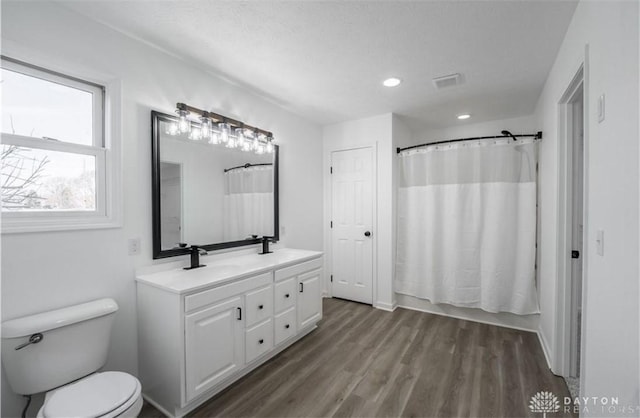 full bathroom with a sink, visible vents, toilet, and wood finished floors