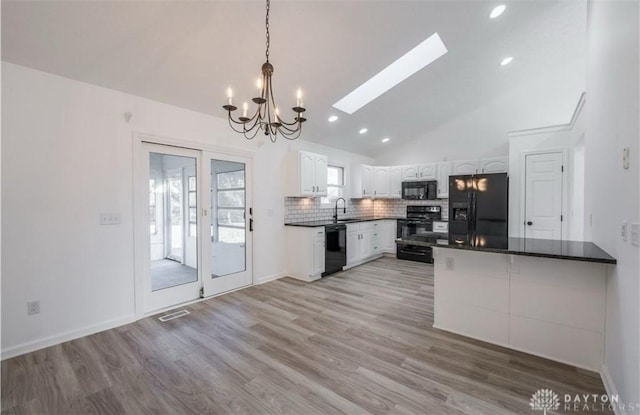 kitchen with dark countertops, backsplash, white cabinets, black appliances, and a sink